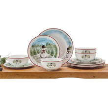 Snowman dinnerware set with bowls, plates, and a cup featuring red trim and snowy forest art