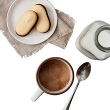 Cookies in a bowl with cocoa drink, spoon, and extra cookie on plate