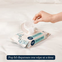 Hand pulling one baby wipe from pack, showing seal and blue floral print