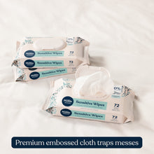 Sensitive wipes packs with pop-top lids stacked, showing embossed cloth design