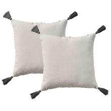Two ivory square throw pillows with dark tassel fringe corners and solid fabric.