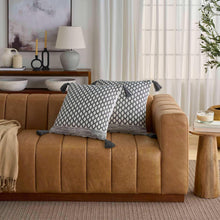 Two gray geometric diamond-pattern throw pillows with tassel trim on sofa.