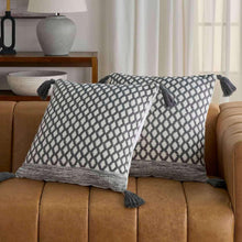 Two navy-and-white geometric diamond throw pillows with dark tassel trim.