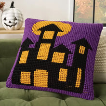 Purple knitted Halloween pillow with black haunted-house silhouette and yellow windows