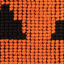 Close-up of orange and black knitted pumpkin-face pattern pillow