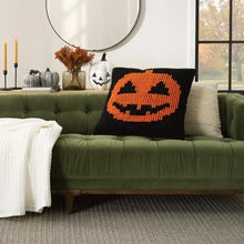 Black knitted pillow with orange jack-o’lantern face, square front
