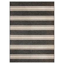 Outdoor area rug with horizontal black and ivory stripes in alternating widths