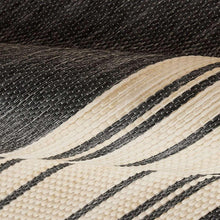 Area rug close-up: dark textured weave with ivory and black horizontal stripe bands.