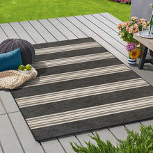 Outdoor area rug with black and ivory striped bands, woven texture, flat weave