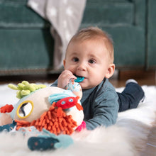 Baby playing with a plush sea animal sensory toy on a soft cushion