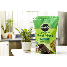 Sphagnum peat moss bag standing beside a small leafy plant in a white pot