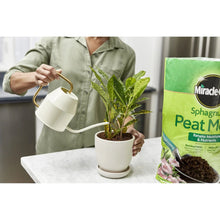 Sphagnum peat moss bag next to a potted plant with peat being poured in