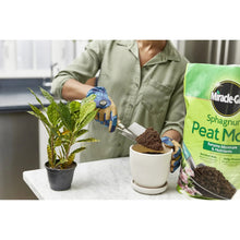 Sphagnum peat moss bag beside a potted plant, with dark peat in the pot