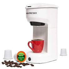 White single-serve coffee brewer with side cups, red mug, and coffee pods and grounds