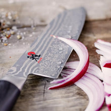 Santoku knife closeup of patterned steel blade with black handle and red-accent ring