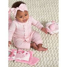 Pink plush sensory ball with rose and polka-dot fabric on textured play mat