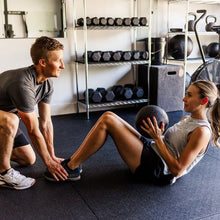 Black rubber gym mat laid on the floor under a workout space