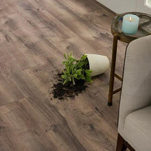 Grey-brown wood plank laminate flooring beside a cushioned chair