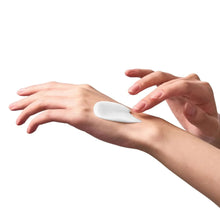 Firming skincare: white cream spread on forearm with fingertips