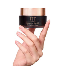Firming expert cream jar held in hands, rose-gold lid on black container