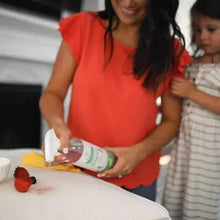 Cleaner bottle being used to spot clean with a yellow cloth on a white table