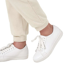Beige jogger pants with tapered cuffs and white lace-up sneakers.