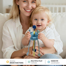 Blue pull-string sensory toy held by baby, with dangling legs and buttons.
