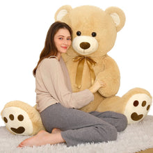 Tan teddy bear plush with gold neck bow, posed while sitting