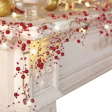 Red berry-beaded light string garland draped with warm white glowing LEDs
