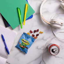 Assorted fruit snack pouch with scattered fruit gummies and a nearby soda can