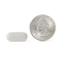 White coated glucosamine tablets beside a quarter for size comparison