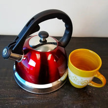 Red stainless steel tea kettle with black handle and spout