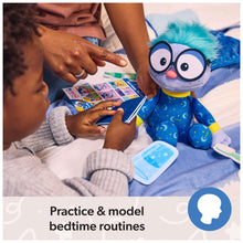 Frankie plush in blue pajamas as child touches board-book cards and bedtime items