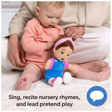Ms. Rachel plush doll in blue overalls with pink hood, posed on a baby’s lap