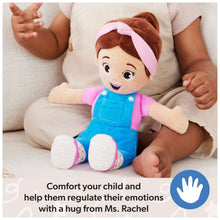 Plush doll in blue overalls with pink hood, seated on a couch with children