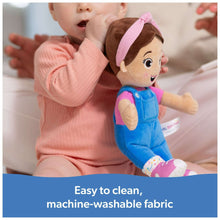Plush doll in blue overalls with pink hood and striped socks, held by a baby