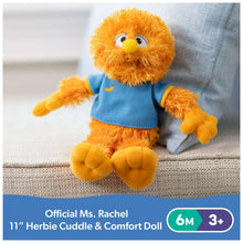 Orange bird plush with blue shirt and yellow beak, resting on a sofa cushion