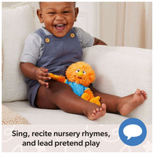 Orange bird plush with blue shirt and wide eyes, held on a couch by a baby