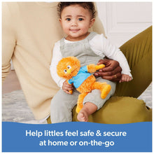 Orange plush bird with blue shirt and yellow beak, held close by a child on a sofa
