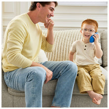 Child holding a blue learning phone to their ear while a parent talks on the couch