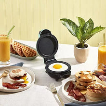 Mini waffle maker with open plates, cooking egg on the lower plate