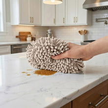 Gray noodle hand towel with dense pom-pom loop fabric, held flat on a countertop