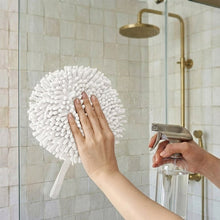 White noodle hand towel with dense pom-pom loop texture, hand pressing against shower wall