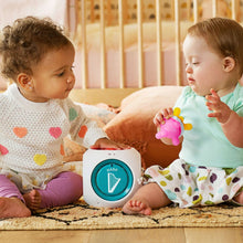 White music cube toy on floor with blue speaker button visible