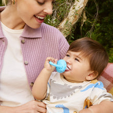 Baby drinking from blue silicone food feeder with caregiver holding nozzle