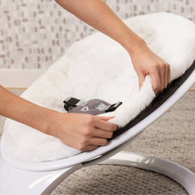 White faux fur seat cover being fitted over infant swing harness