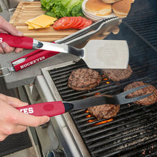 Stainless grill spatula and fork with red handles on a barbecue grate