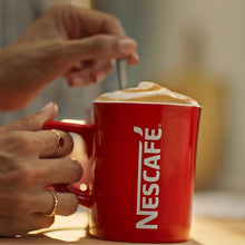 Red NESCAFE mug with hands pouring coffee
