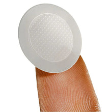 Round pimple patch on fingertip, grey backing with dotted inner layer