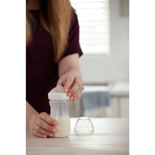NUK Simply Natural baby bottle held in hands; clear bottle with white nipple